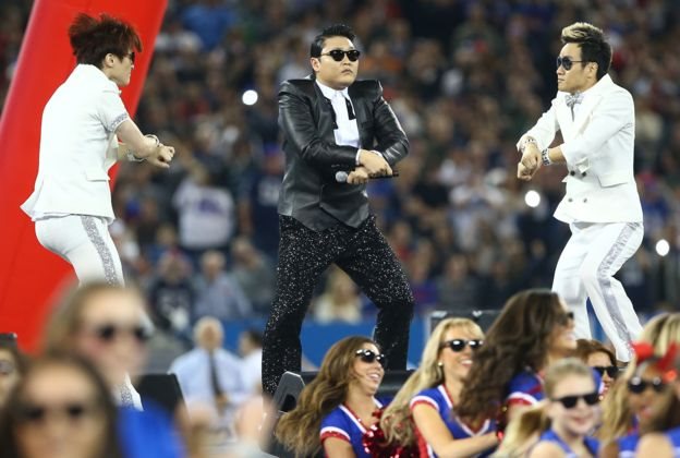 Співак Psy виконує рухи танцю Gangnam Style на сцені з двома танцюристами