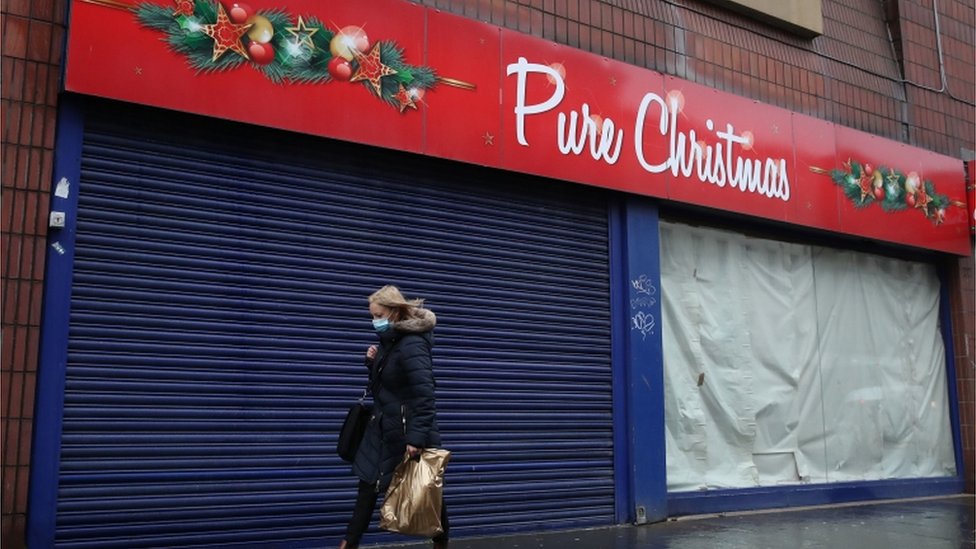 Женщина проходит мимо закрытого магазина в Глазго