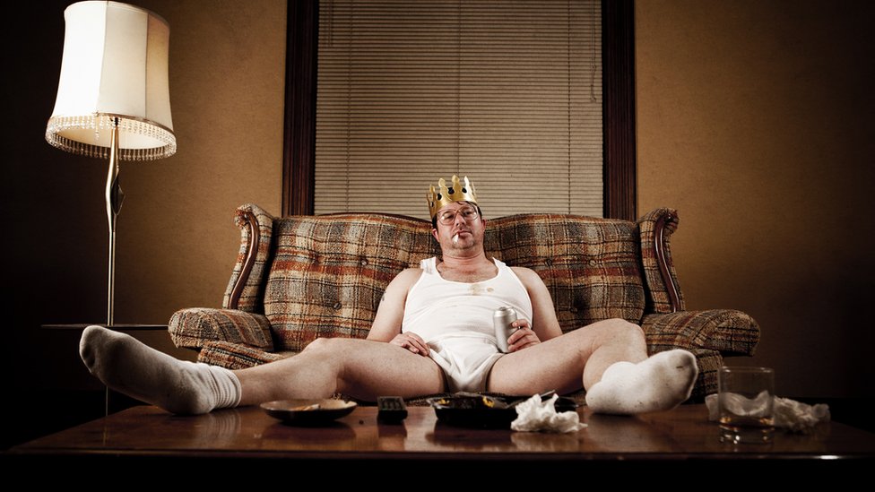 Hombre en sofá con corona de rey en ropa interior