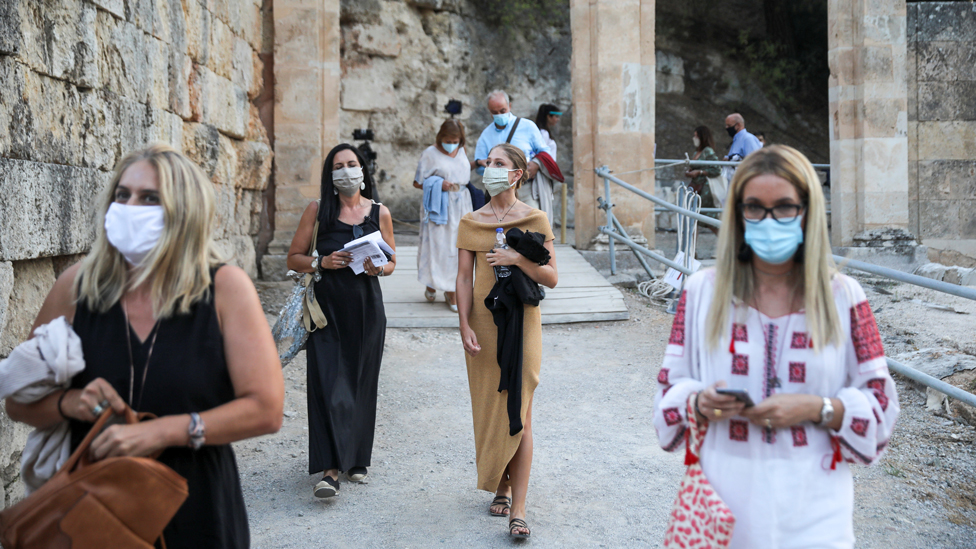 People wearing protective face masks enter the ancient amphitheatre of Epidaurus