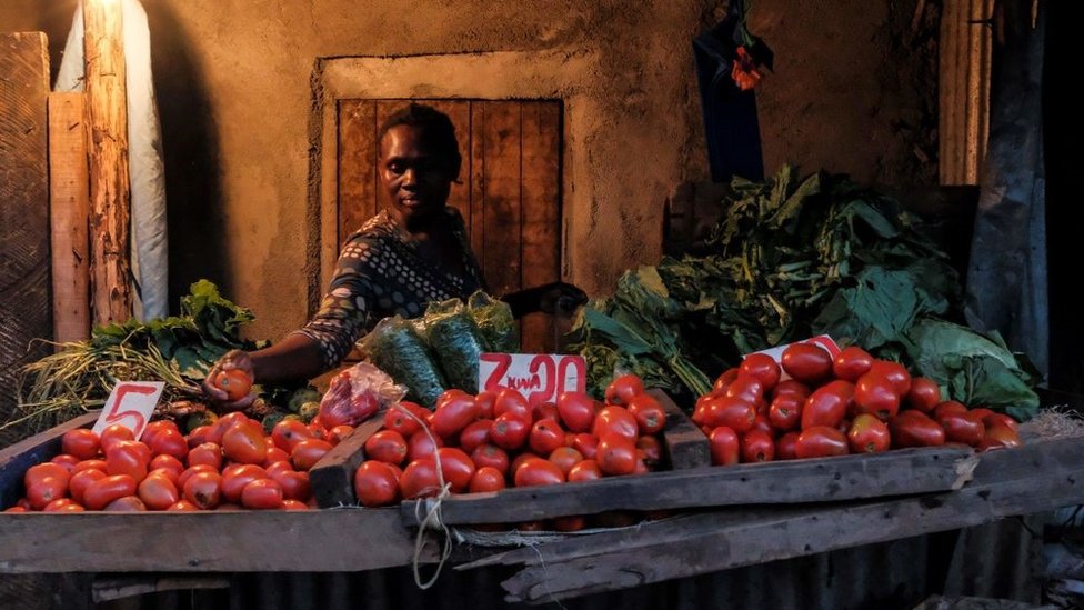 Uma mulher faz uma seleção dos tomates mais caros para um cliente, pouco antes do toque de recolher das 19h em Kibera, Nairobi, em maio de 2020