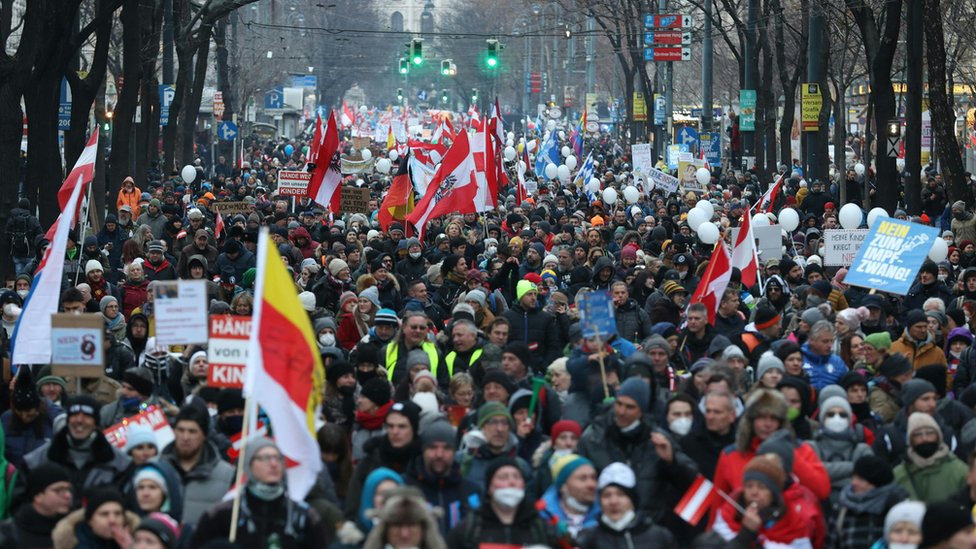 People carry Austrian flags as they demonstrate against the Austrian government's Covid measures on 8 January