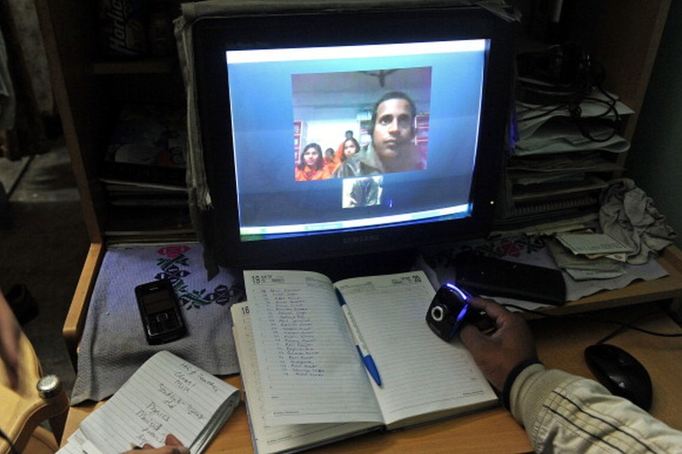 Gurukul Trust, Сантош Кумар (справа), проводит онлайн-класс из Нью-Дели для студентов из отдаленной деревни в Бихаре, чтобы принести образование в индийскую деревню. Раз в неделю Кумар использует компьютерную программу Skype для обучения математике детей в Чаманпуре, бедной деревне в бедствующем штате Бихар, в 600 милях (970 км)