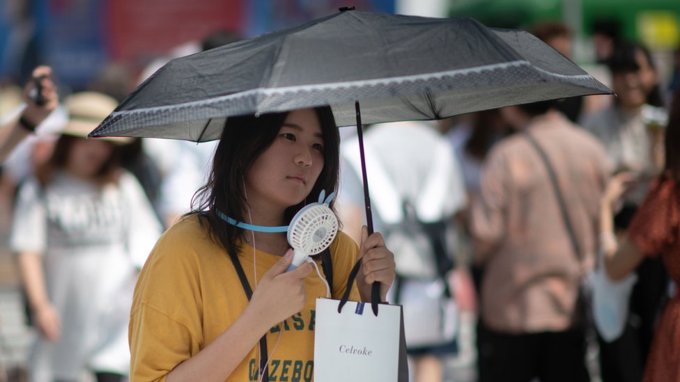 Una mujer usa un ventilador portátil para combatir el calor en Japón.