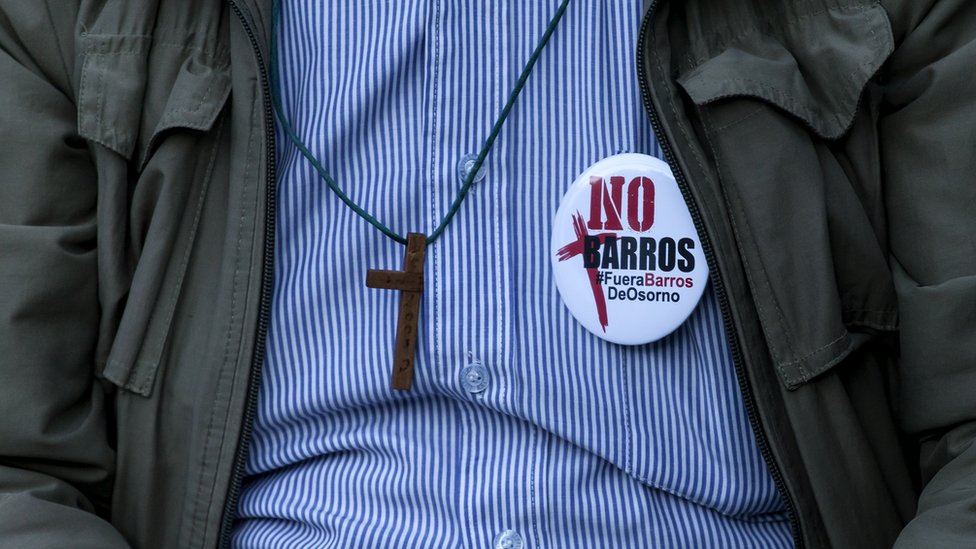 La decisión de la Iglesia Católica de nombrar a uno de los cercanos de Karadima, Juan Barros, como Obispo de Osorno, gatilló la división entre los fieles de la ciudad sureña, la presión de los laicos, los medios y la ciudadanía y, finalmente, la intervención del Papa y una crisis sin precedentes en la iglesia chilena. Hombre con chapa "No Barros"