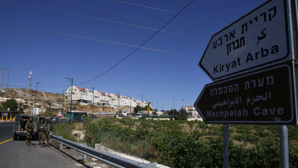 Израильские солдаты охраняют дорогу возле еврейского поселения Кирьят-Арба, где 30 июня в своей спальне была смертельно ранена 13-летняя израильская девочка