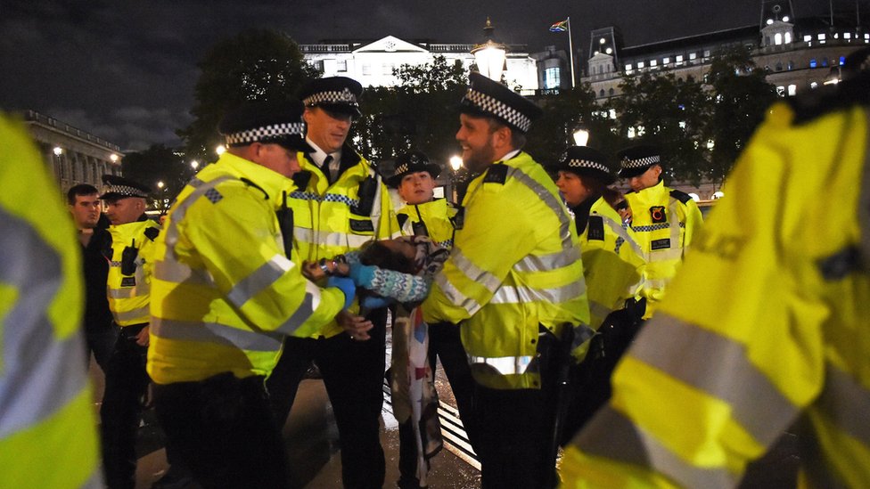 Police remove an Extinction Rebellion protester from Trafalgar Square in central London.