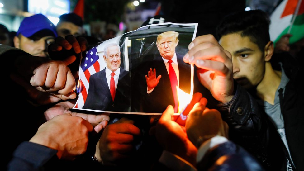 Палестинские демонстранты сжигают фотографии президента США Дональда Трампа и премьер-министра Израиля Биньямина Нетаньяху во время демонстрации в городе Рамаллах на Западном берегу реки Иордан