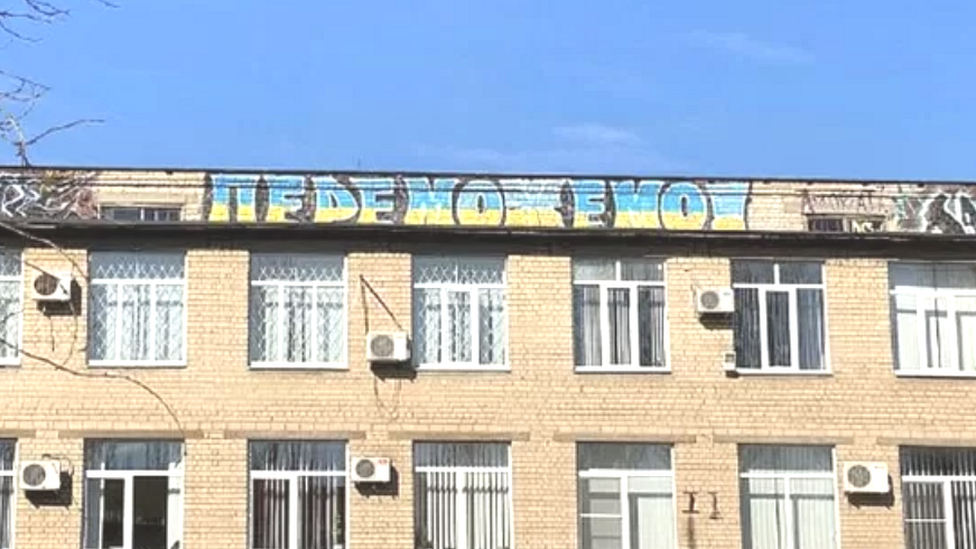Grafit „Pobedićemo" u bojama ukrajinske zastavae na zgradi u Melitpolju