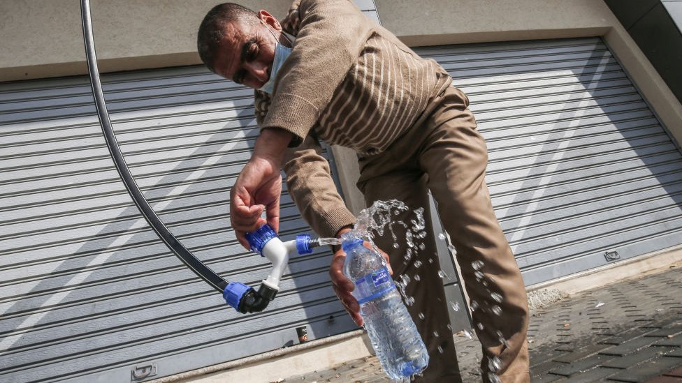 A man pouring water into a plastic bottle