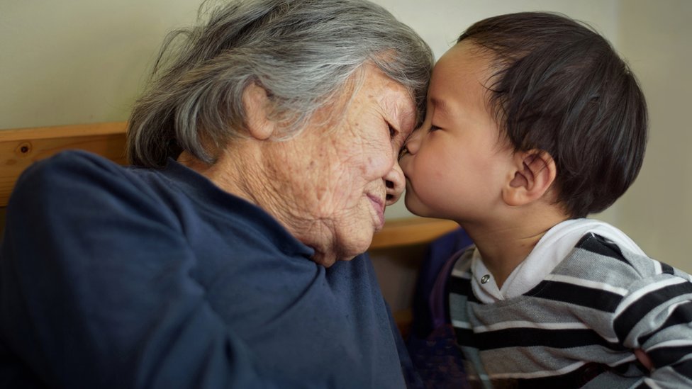 Китайский ребенок целует женщину постарше - стоковое изображение