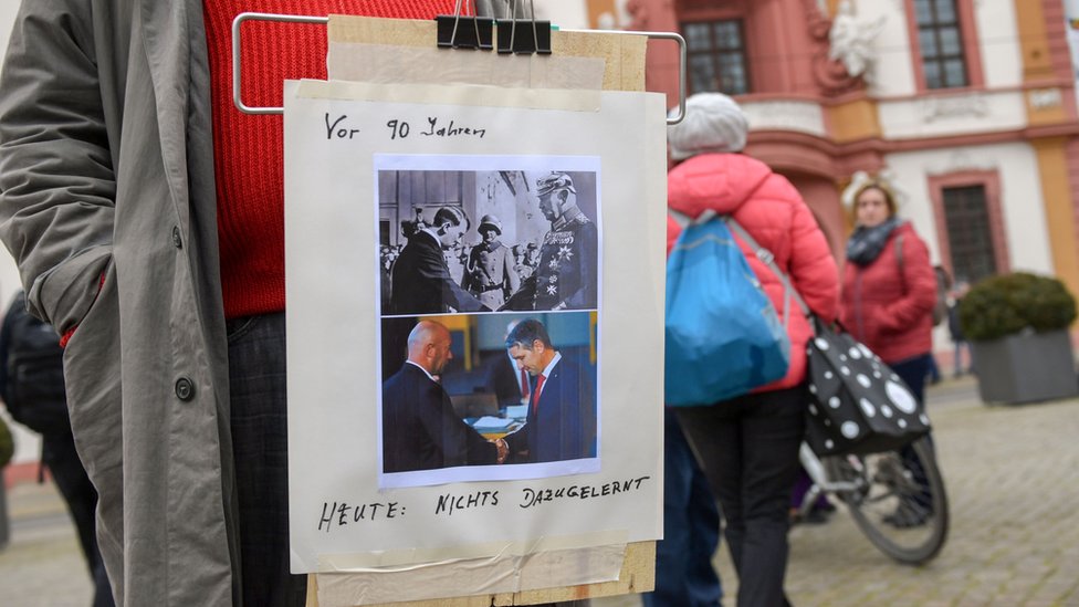 Протестующий в Германии с фотографией сравнивает недавние выборы лидера Тюрингии с выборами Адольфа Гитлера