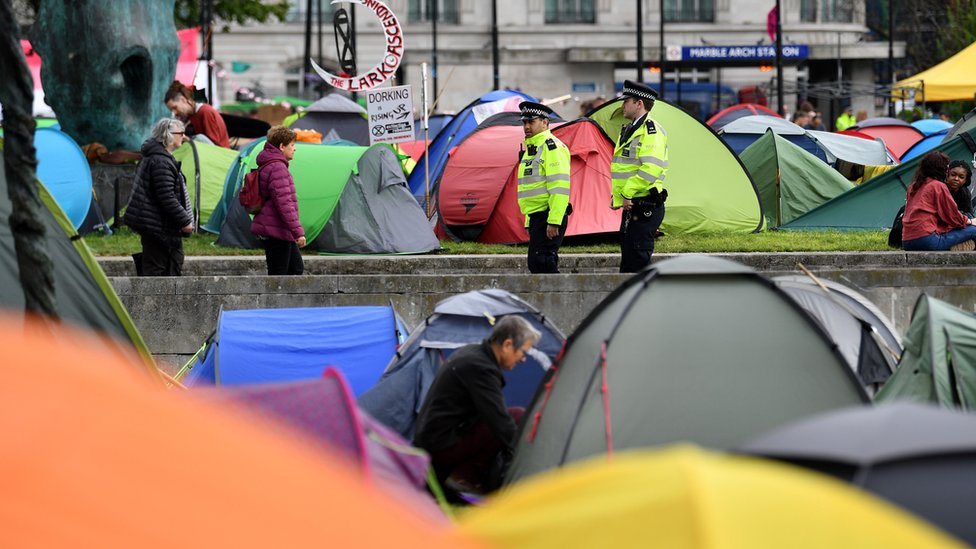 Полицейские идут среди палаток в экологическом лагере протеста группы Extinction Rebellion на Мраморной арке в Лондоне
