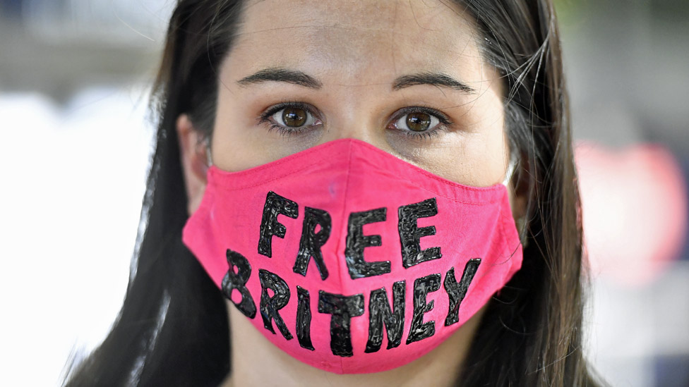 Una fan Britney Spears con una mascarilla que dice "Free Britney"