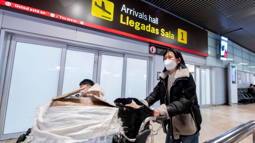 Seorang perempuan mendorong troli di bandara Spanyol.