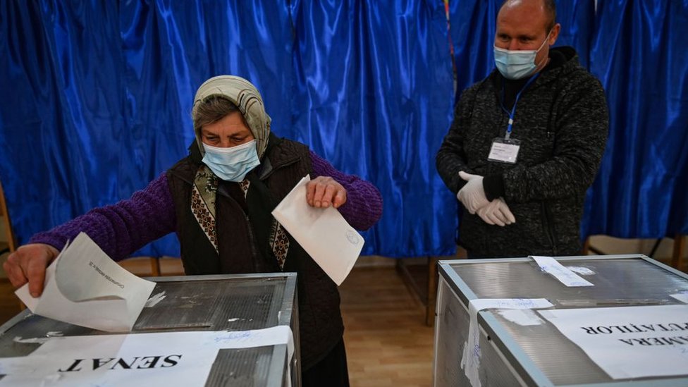 A woman casts her ballot at a polling station in Sintesti village, southern Romania, during the parliamentary elections on December 6, 2020