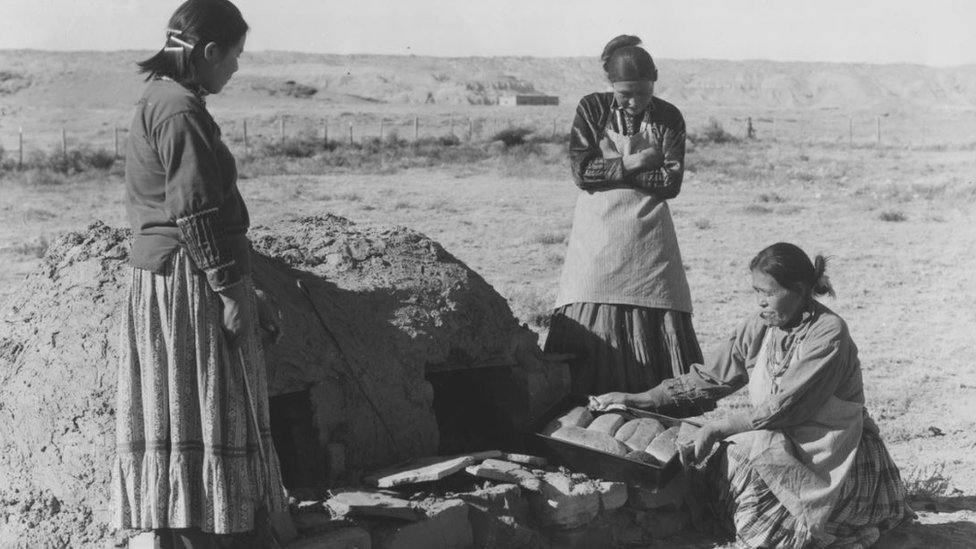 Un grupo de mujeres navajo hornean pan en un horno de barro en esta imagen de la primera mitad del siglo XX.