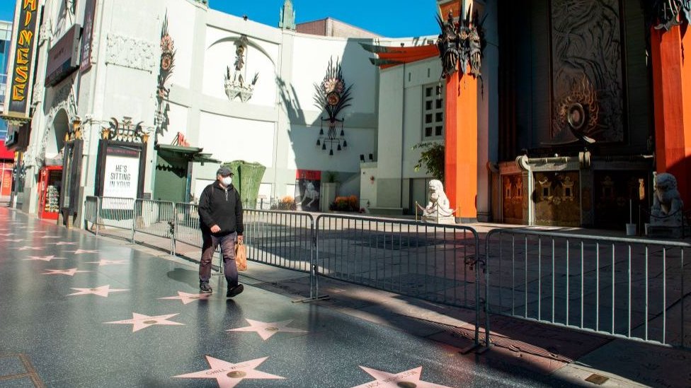 Un hombre camina por un desértico Paseo de la Fama de Hollywood.