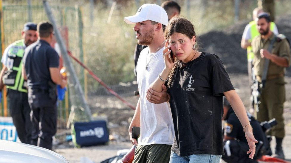 رجل وامرأة يسيران في موقع هجوم بالقرب من مستوطنة عيلي اليهودية في شمال الضفة الغربية المحتلة