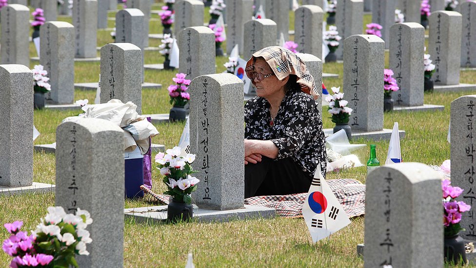Mujer frente a la tumba de un familiar de la guerra.