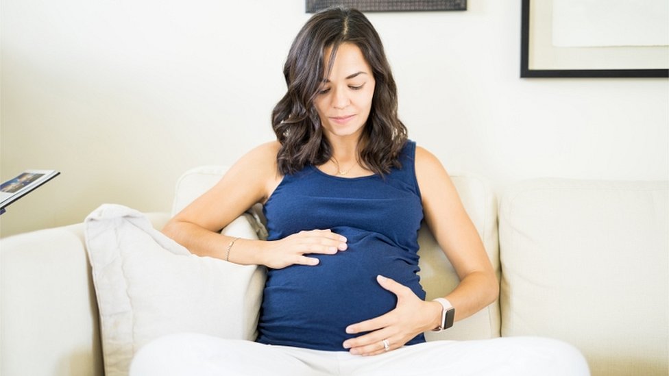 Беременная женщина трогает и смотрит на живот