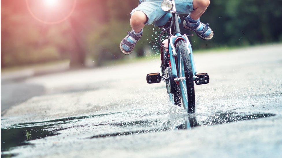 Hay momentos inolvidables. Chico montando bicicleta en charco