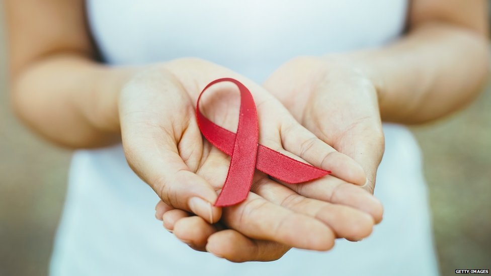 A woman's hand holding a red ribbon