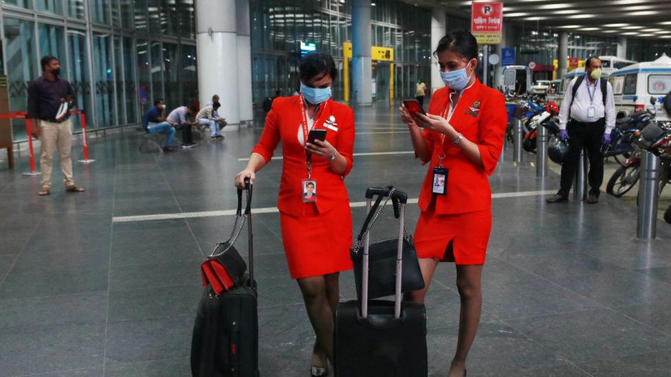 Стюардесса AirAsia Airlines в часах с защитной маской на своем смартфоне в международном аэропорту Нетаджи Субхас Чандра Бос, 4 июня 2020 года в Калькутте, Индия.