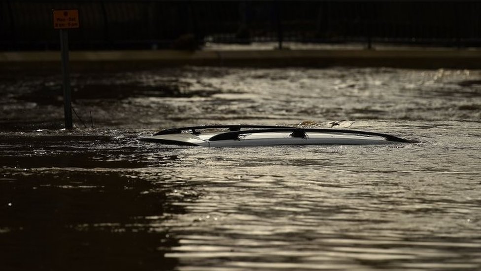 Крыша затонувшего автомобиля изображена на затопленной улице в Митхольмройде, северная Англия