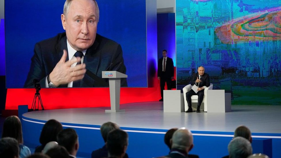 Vladimir Putin sits on stage at election headquarters in Moscow, Russian Federation with a big screen behind him showing his face on 31 Jan 2024