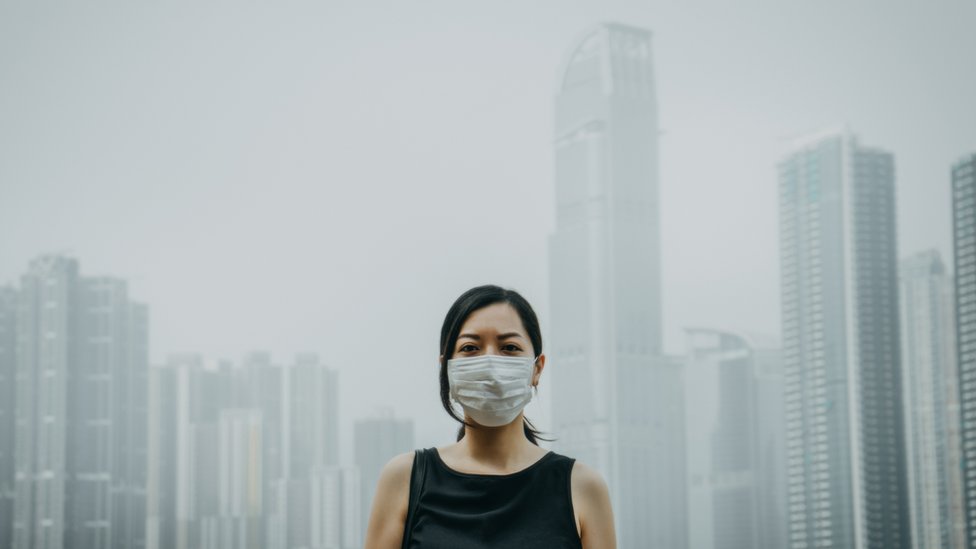 Una persona con tapabocas en una ciudad contaminada.