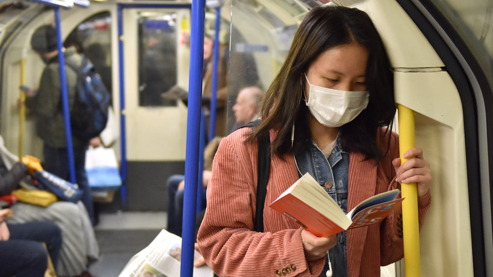 Женщина читает книгу в лондонском метро`