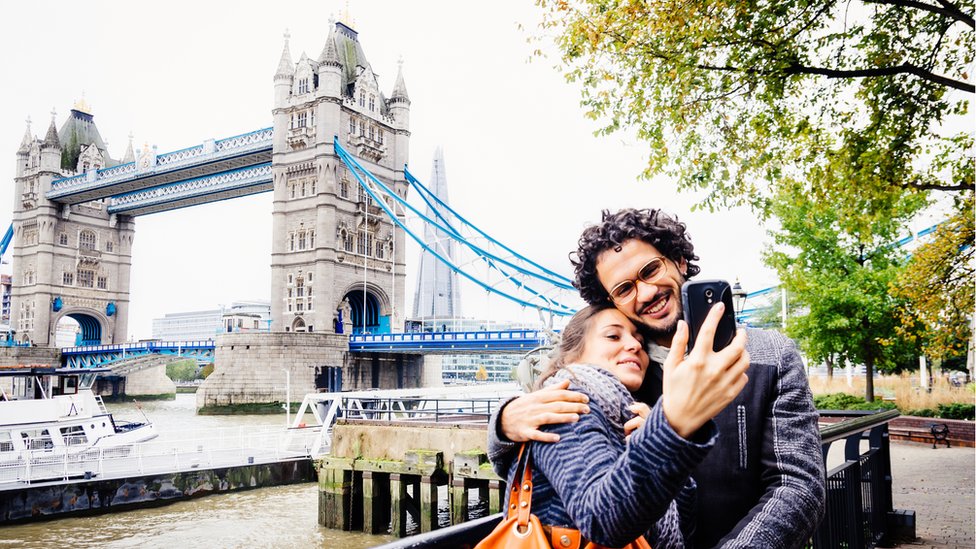 Una pareja se toma una foto frente al Puente de la Torre, en Londres