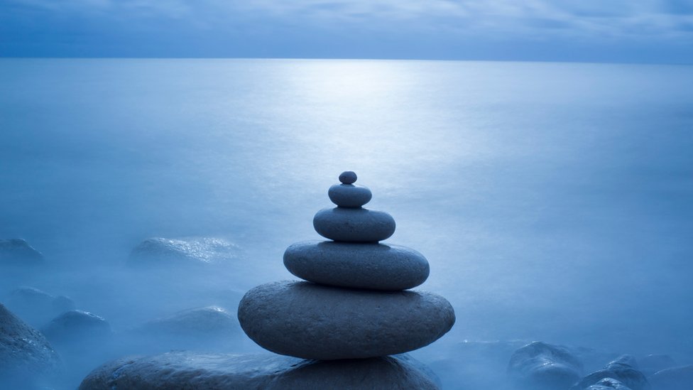 Una pila de piedras una sobre otra en delicado equilibrio frente al mar