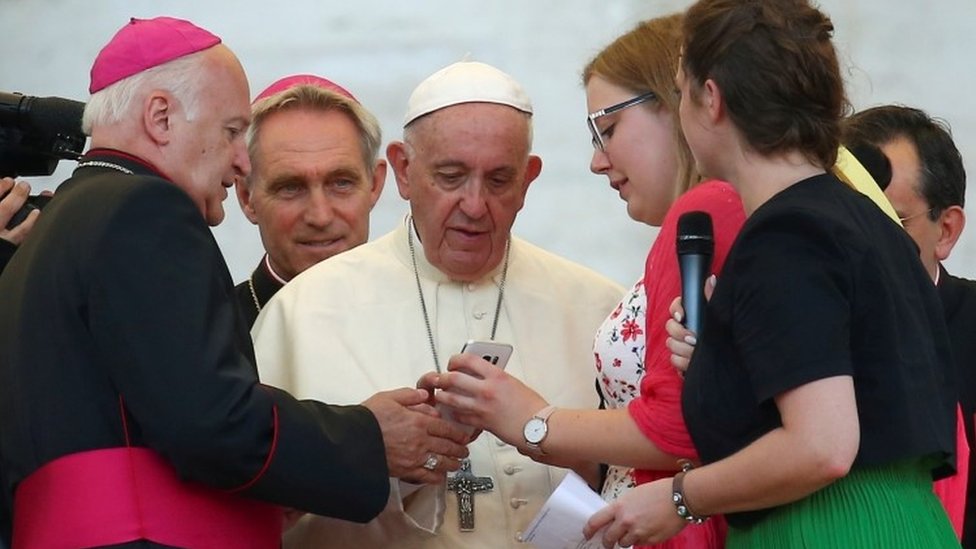 Священник показывает Папе Франциску телефон