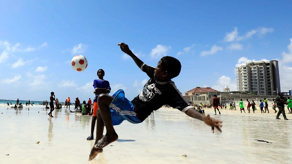 Boy playing football on the beach