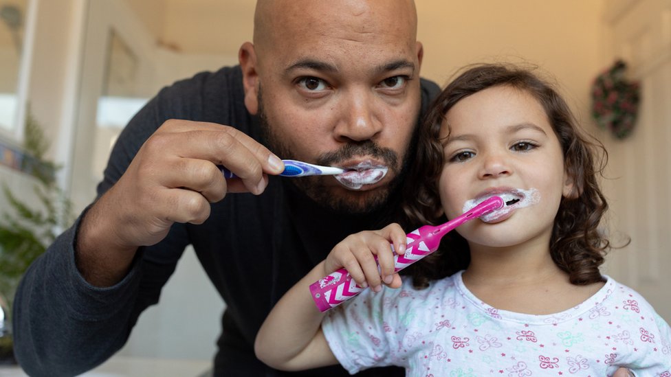 Padre e hija lavándose los dientes