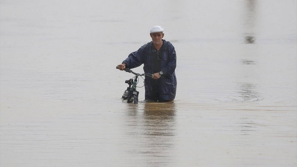 Hombre en biccleta en medio de una inundacion