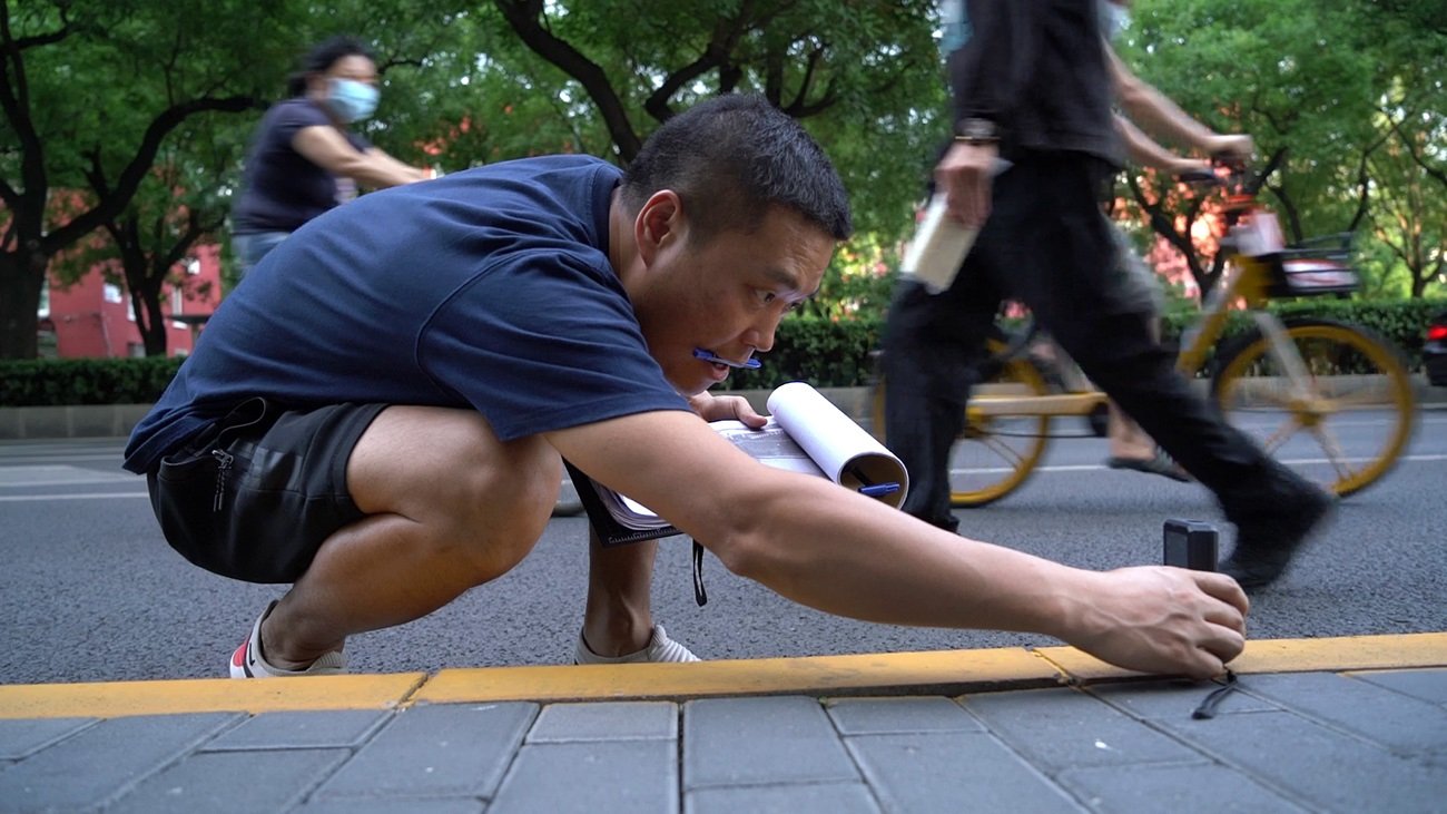 鄧玉峰通過測距儀測量路面長度。