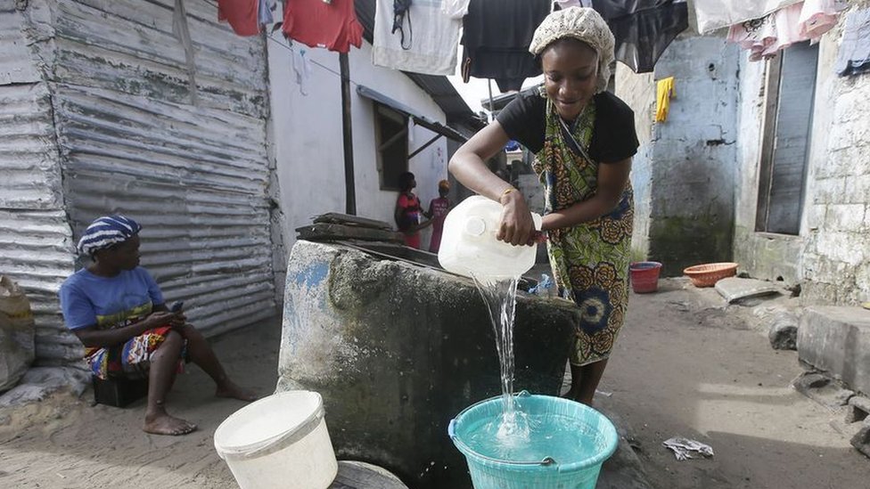 A woman prepares to wash clothes in a South African slum