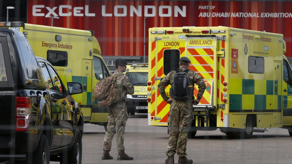 Military personnel stand near London Ambulance Service vehicles at the new NHS Nightingale Hospital at ExCeL London on March 25, 2020 in London, England.