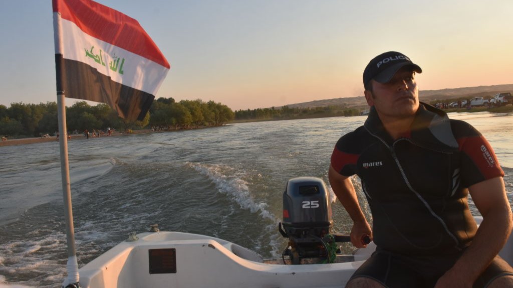 رجل يركب زورقا بينما يسبح الناس في نهر الزاب الكبير بعد أن وصلت درجات الحرارة إلى 45 درجة في بلدة ألتونكوبرو، كركوك، العراق في 20 يوليو/تموز2020