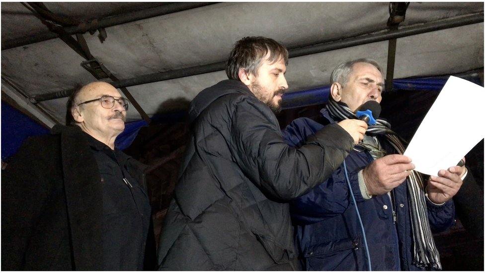 Branislav Trifunović (u sredini) drži mikrofon za novinara Milanu Jovanović (desno) u tokom obraćanja učesnicima protesta. Karikaturista Dušan Petričić (levo) takođe je bio među govornicima.