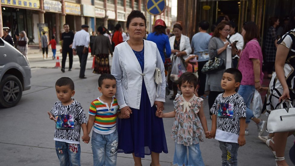 This file photo taken on June 4, 2019 shows a Uighur woman waiting with children on a street in Kashgar in China`s northwest Xinjiang region.