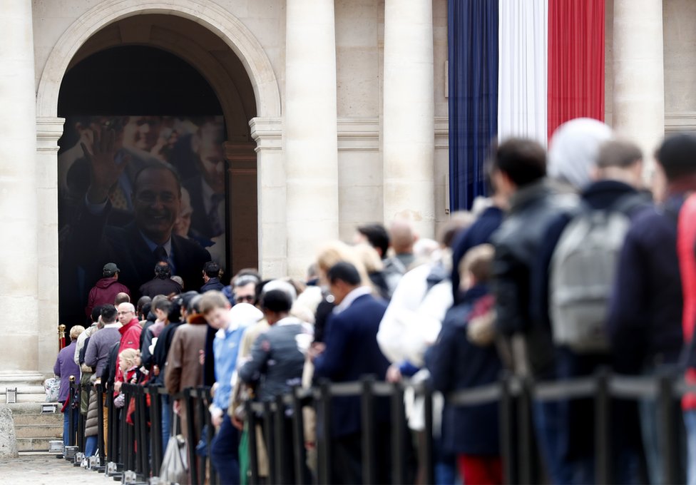 Visitors wait to view the coffin of former French President Jacques Chirac as it lies in state in the Invalides on 29 September 2019.