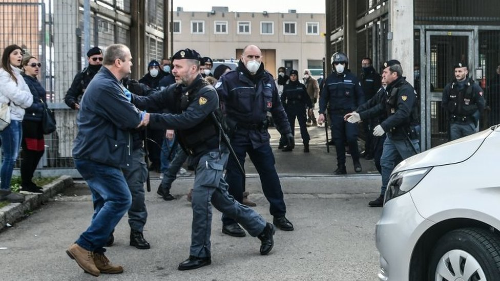Сотрудник полиции удерживает мужчину возле тюрьмы в Модене, Италия. Фото: 9 марта 2020 г.