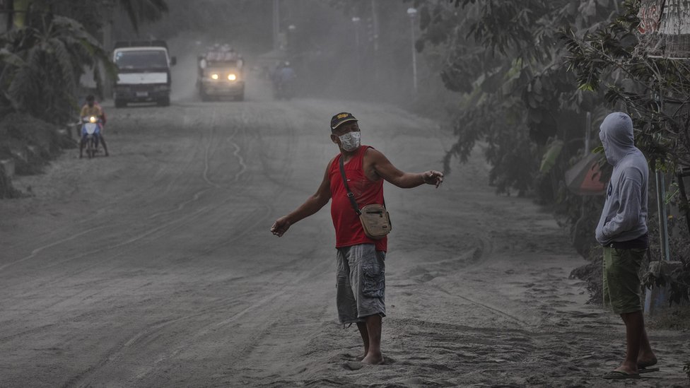 Жители идут по дороге, покрытой вулканическим пеплом от извержения вулкана Таал 13 января 2020 года в Лемери, провинция Батангас, Филиппины