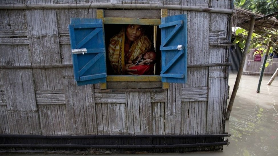 Женщина держит своего 41-дневного мальчика, выглядывая из окна своего частично затопленного дома в деревне Гаголмари в 85 километрах (53 милях) к востоку от Гаухати, Индия, среда, 2 сентября 2015 г.