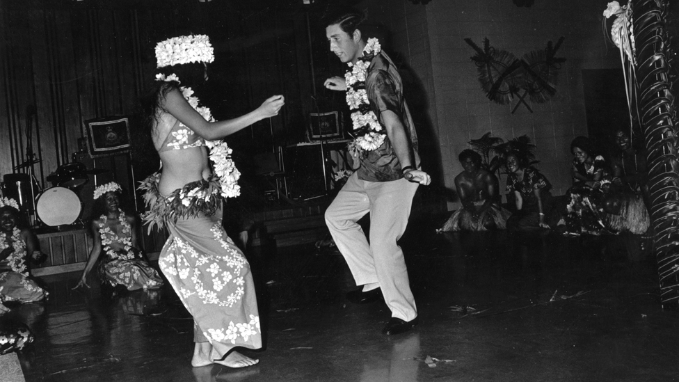 El rey Carlos III bailando con una mujer en un evento social celebrado en su honor durante una gira real en Fiji.