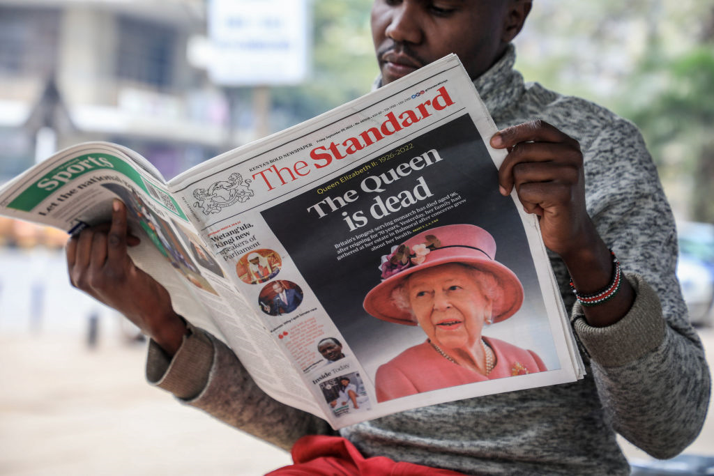 A newspaper vendor seen reading a local daily reporting on the death of Queen Elizabeth II in the city of Nairobi. Queen Elizabeth II